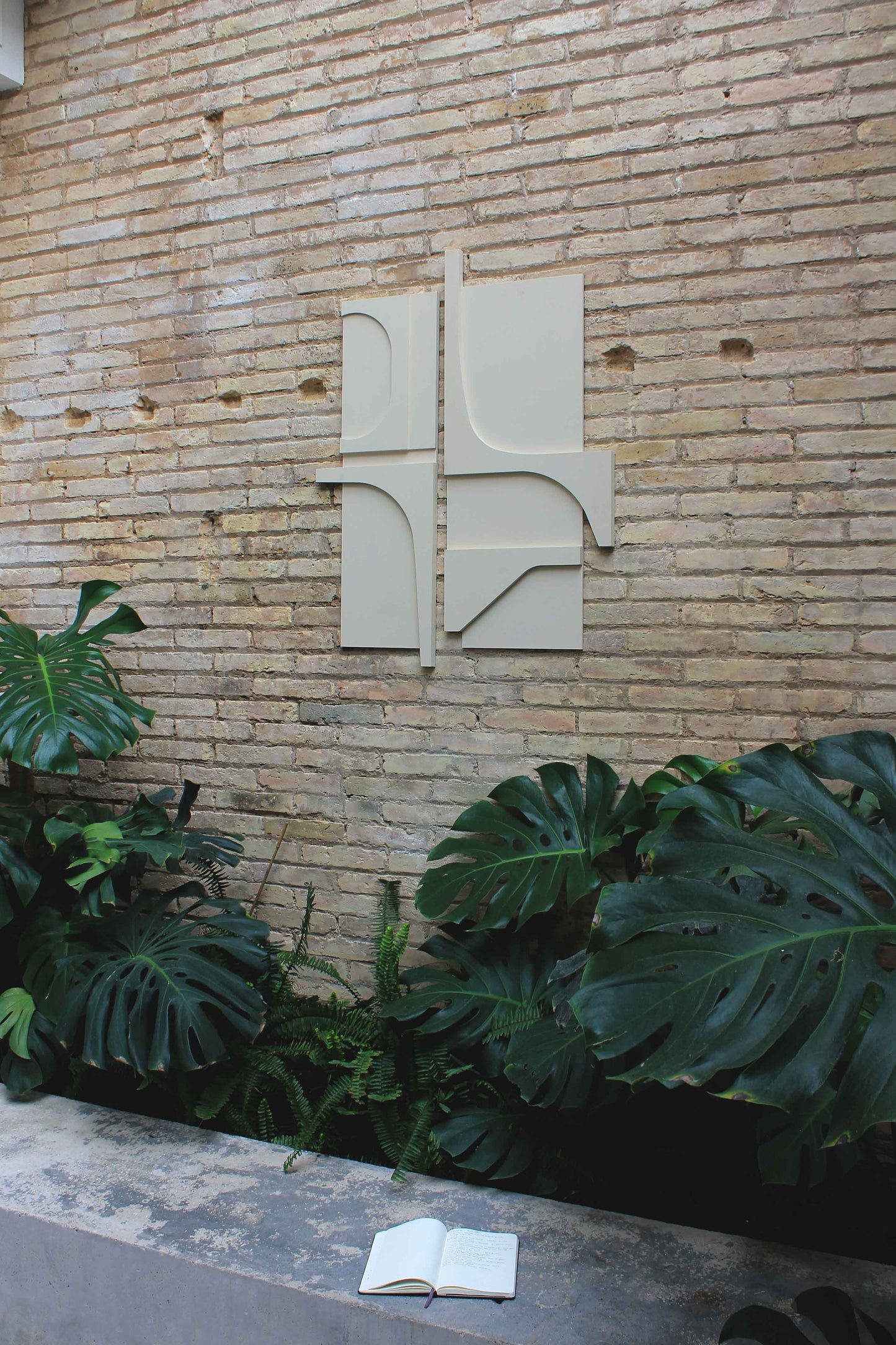 Escultura blanca sobre de ladrillo cara vista. Composición de líneas sinuosas combinadas con ángulos rectos. Un estudio de proporciones y geometría que dan como resultado una obra de aspecto contemporáneo ideal para casas modernas de línea minimalista.