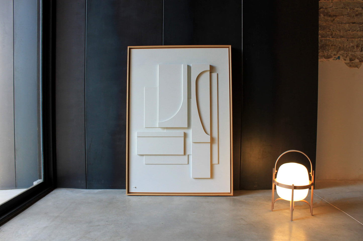 Cuadro blanco grande enmarcado en madera natural. Aparece sobre un fondo negro en una casa moderna de estilo minimalista.