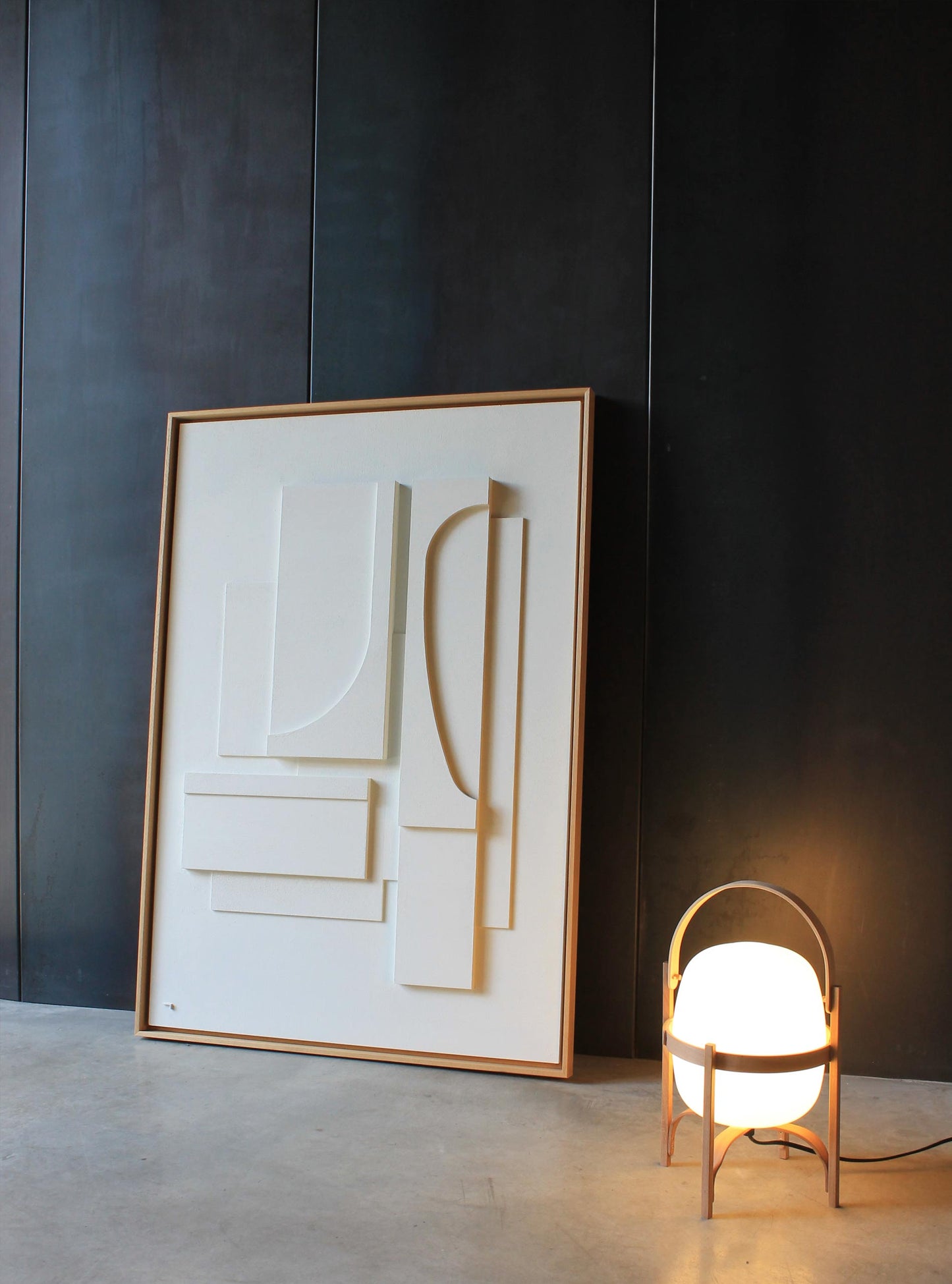 Cuadro blanco grande enmarcado en madera natural. Aparece sobre un fondo negro en una casa moderna de estilo minimalista.