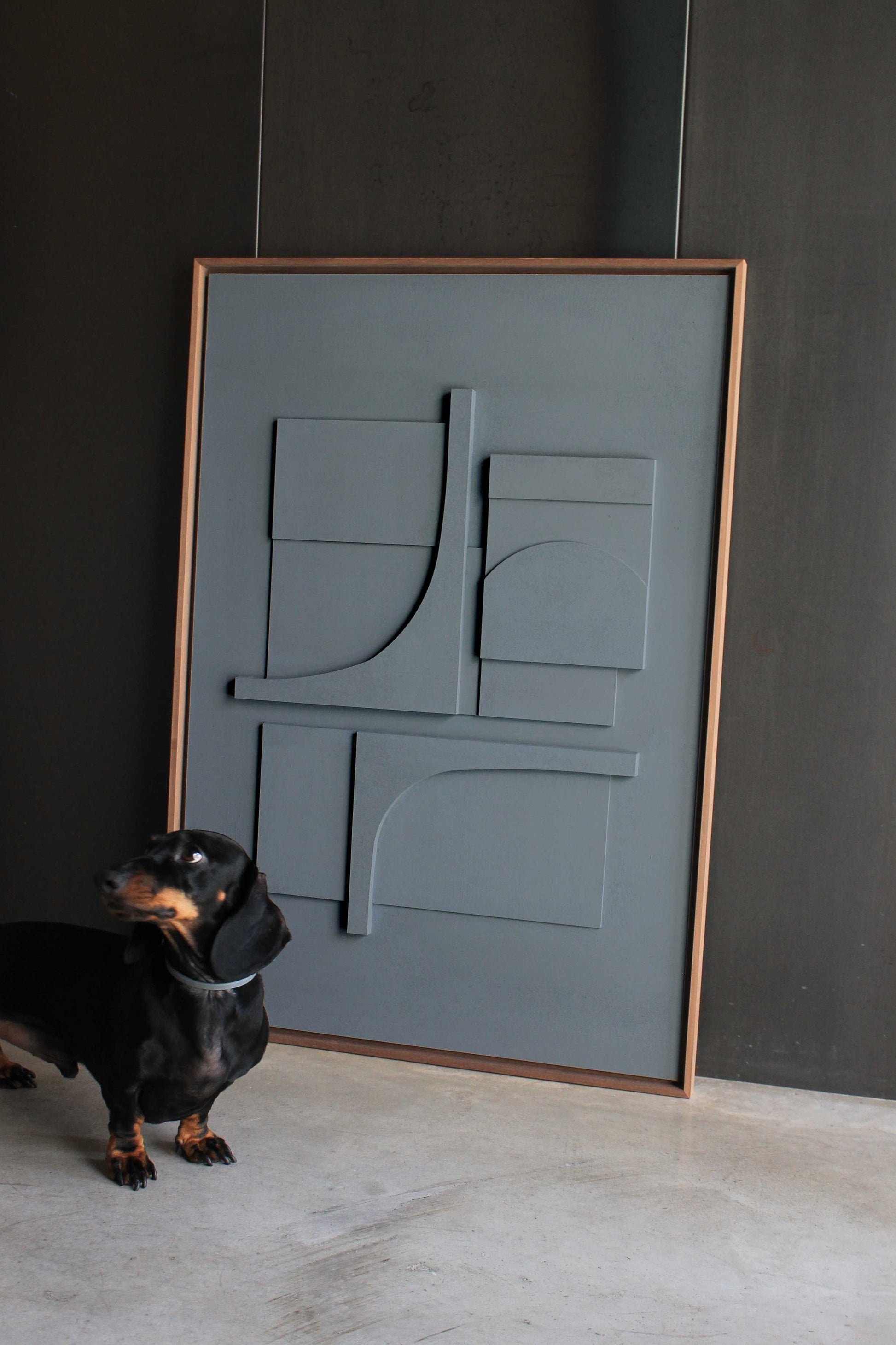 Arte contemporáneo por Teresa Darocas. Fotografía de la obra Carlo (en azul grisáceo) junto a un perro salchicha que ayuda a entender el tamaño del cuadro.